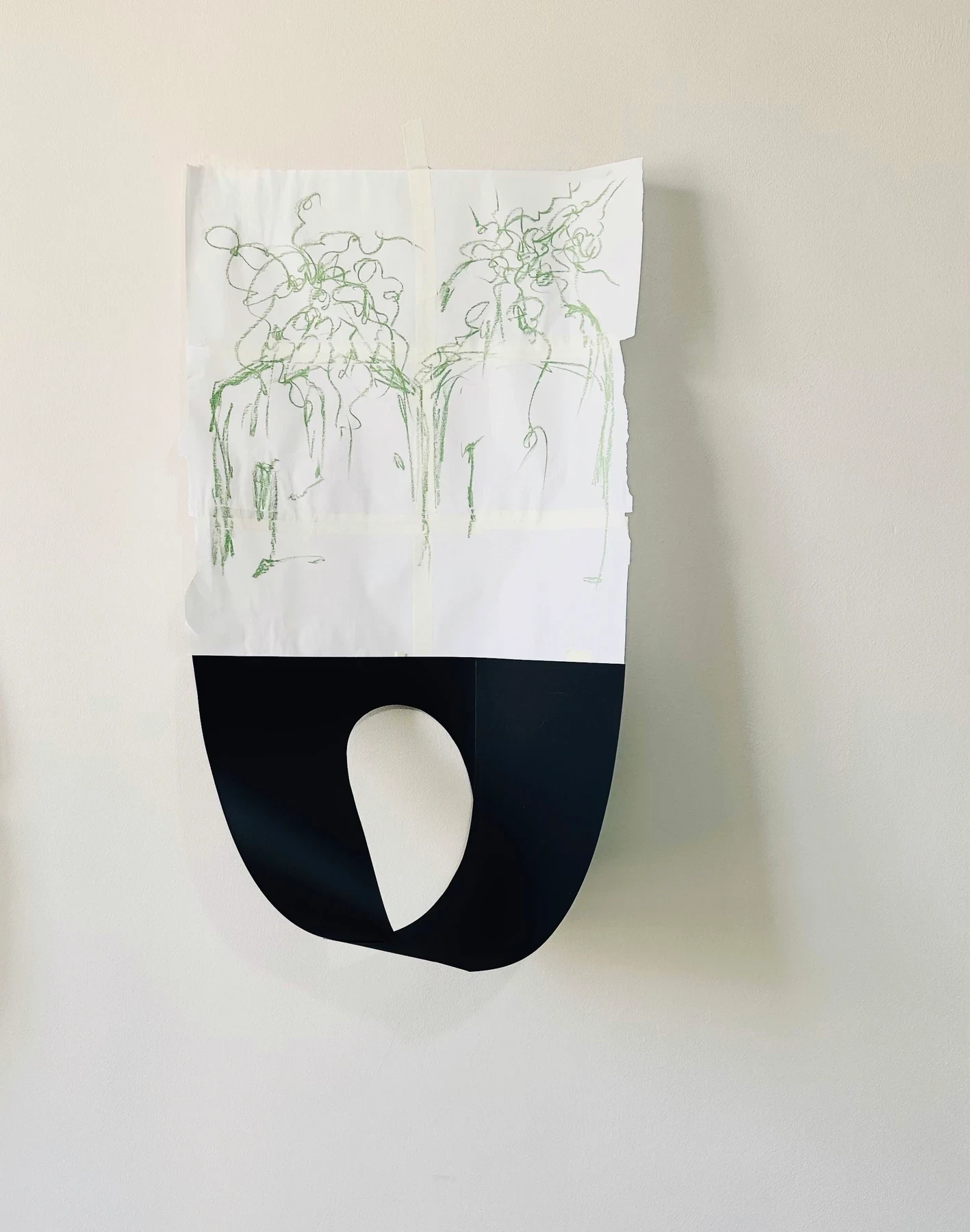 A green drawing on a curled black and white paper work.