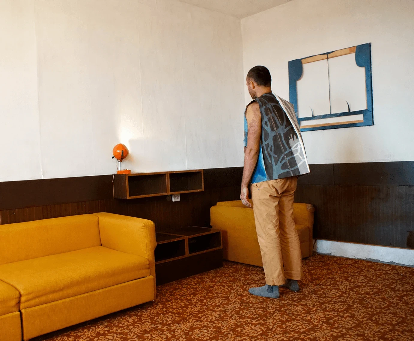 Rear view of a person wearing a painted garment beside a yellow sofa.