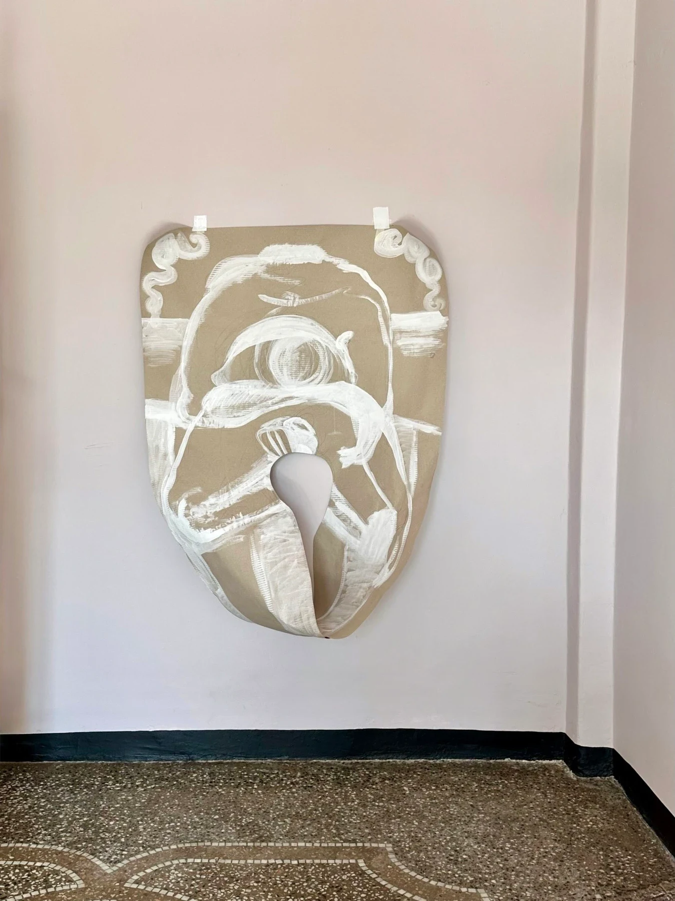 A large pale cut-paper work hanging beside a doorway.
