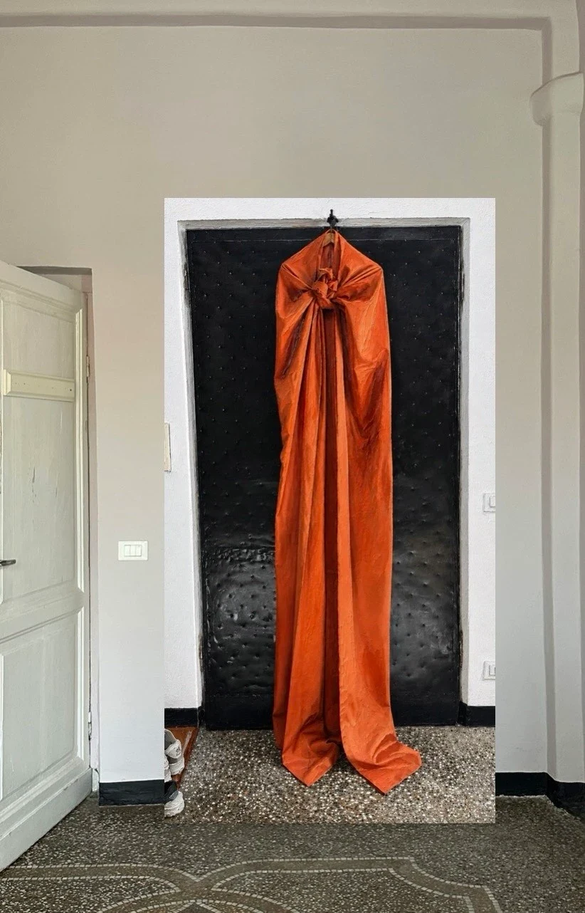 An orange garment hanging in a white doorway.