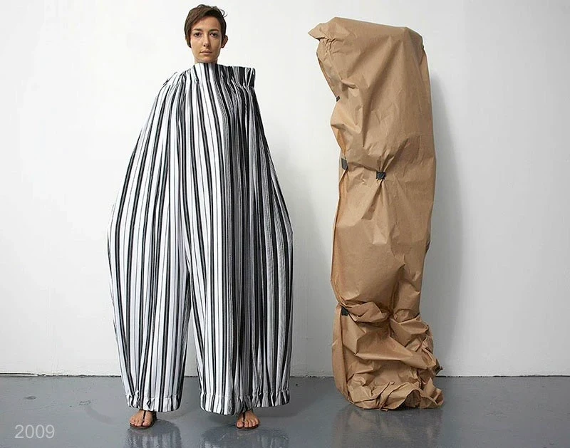 A wide striped garment beside a tall tan paper-like form.