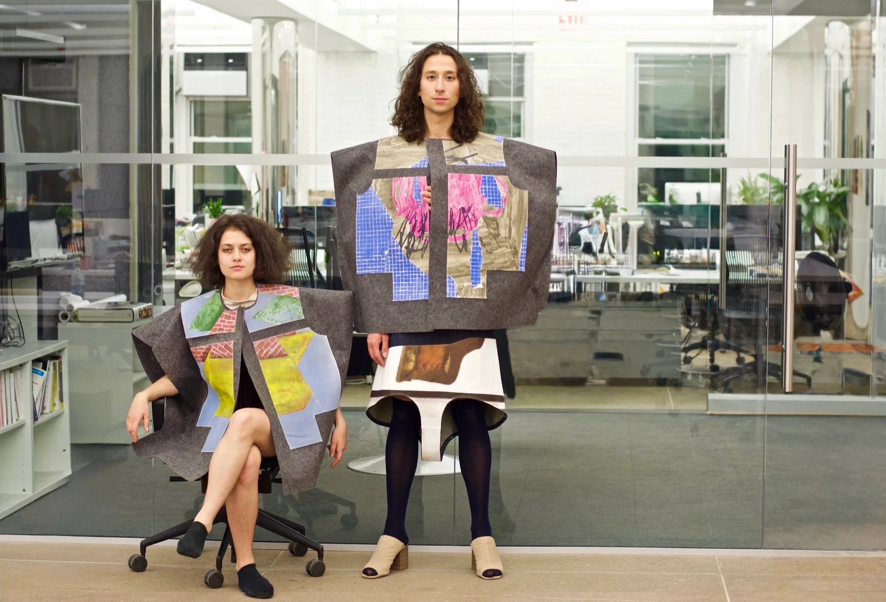 Two people wearing painted NEP garments, one seated and one standing.