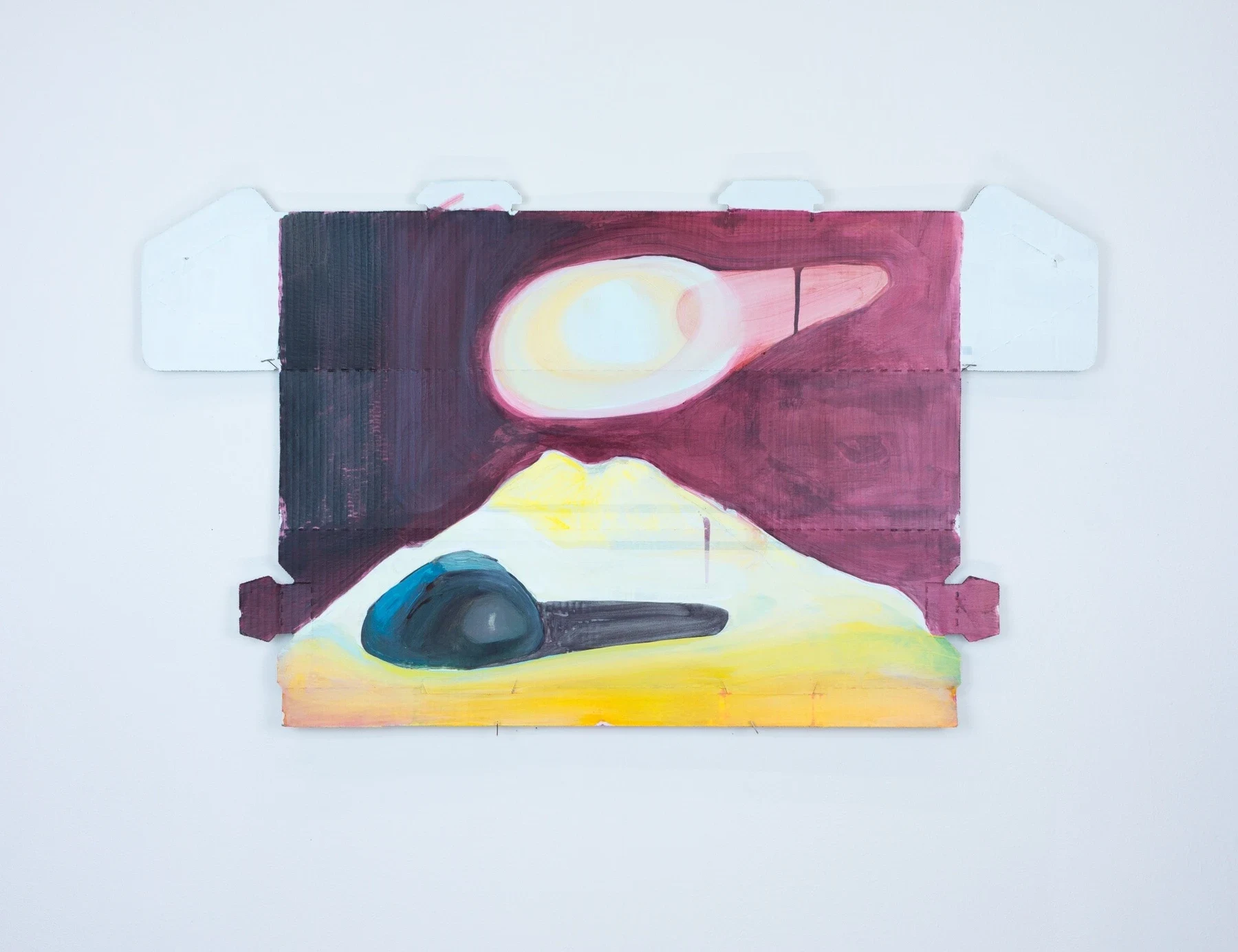 An open cardboard shape painted with pink, yellow, black and blue forms.