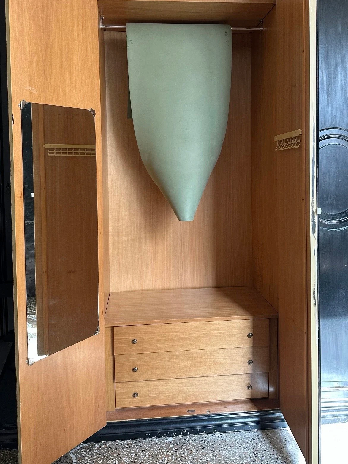 A pale green hanging form inside an open wooden wardrobe.
