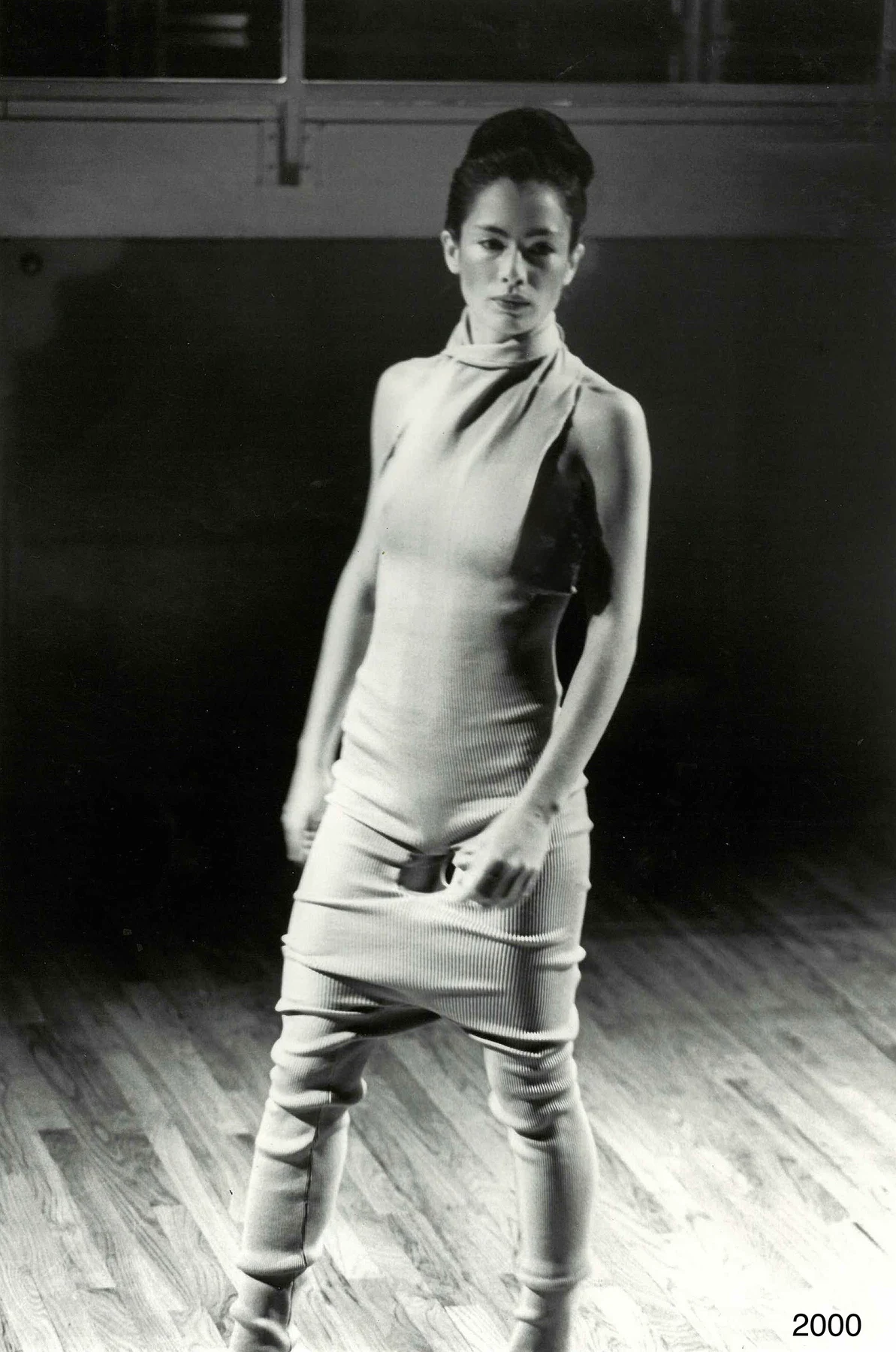 Black and white photograph of a person in a close-fitting draped outfit.